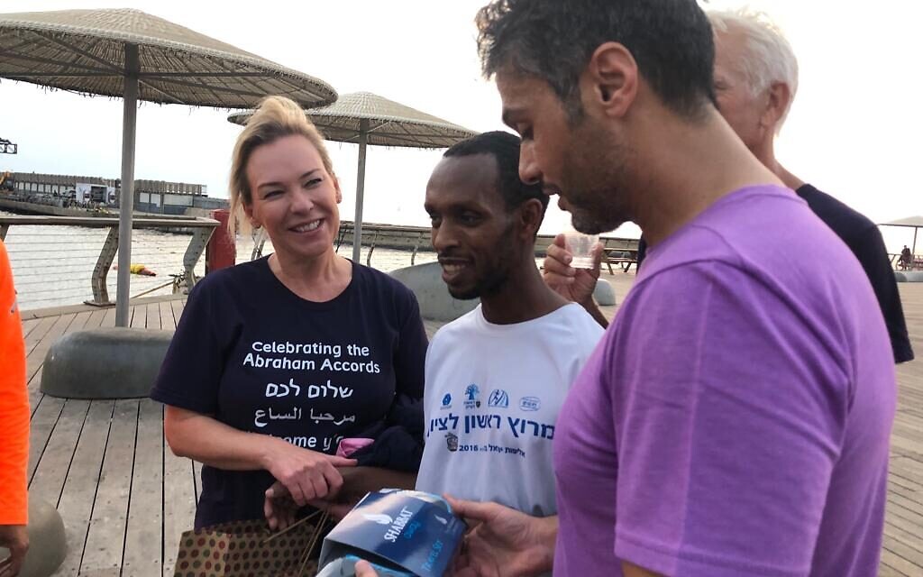 UAE ambassador to Israel Mohamed al Khajah (right) being given a gift of a travel Shabbat kit by blind Israeli  runner Avi Solomon (center), after their run in Tel Aviv, November 18, 2021 (Maria Troyanker/UAE Embassy)