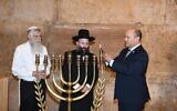 Prime Minister Naftali Bennett (R) lights a candle to mark the first night of Hanukkah at the Western Wall in Jerusalem, November 29, 2021 (Amos Ben-Gershom/GPO)
