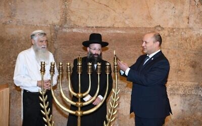 Prime Minister Naftali Bennett (R) lights a candle to mark the first night of Hanukkah at the Western Wall in Jerusalem, November 29, 2021 (Amos Ben-Gershom/GPO) Prime Minister Naftali Bennett (R) lights a candle to mark the first night of Hanukkah at the Western Wall in Jerusalem, November 29, 2021 (Amos Ben-Gershom/GPO)
