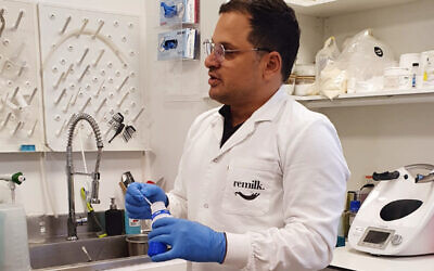 A Remilk scientist holds a bottle with the company's proprietary cow-free milk in powder form, at the startup's office in Rehovot, November 2021. (Times of Israel staff)
