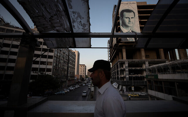 Illustrative: A Syrian man walks over a bridge past a campaign poster of President Bashar Assad in the Syrian capital Damascus, on May 25, 2021. (AP Photo/Hassan Ammar) Illustrative: A Syrian man walks over a bridge past a campaign poster of President Bashar Assad in the Syrian capital Damascus, on May 25, 2021. (AP Photo/Hassan Ammar)
