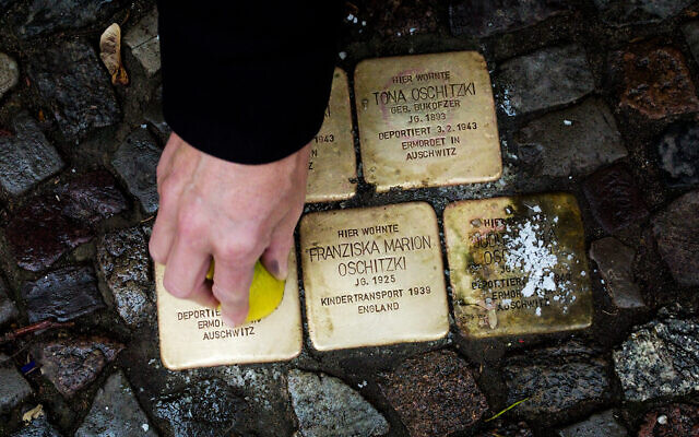 A local resident polishes a so-called 'Stolpersteine' or 'stumbling stones' commemorating people deported and killed by the Nazis in front of his house in Berlin, Germany, Nov. 9, 2021, the 83th anniversary of the Nazis' anti-Jewish Kristallnacht pogrom in 1938. (AP Photo/Markus Schreiber) A local resident polishes a so-called 'Stolpersteine' or 'stumbling stones' commemorating people deported and killed by the Nazis in front of his house in Berlin, Germany, Nov. 9, 2021, the 83th anniversary of the Nazis' anti-Jewish Kristallnacht pogrom in 1938. (AP Photo/Markus Schreiber)