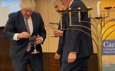 UK Prime Minister Boris Johnson tends to his broken menorah, November 29, 2021 (Youtube screenshot)