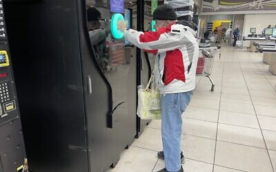 A shopper tries out the bottle deposit automat at a Talpiot, south Jerusalem, branch of the Yochananoff supermarket chain, November 23, 2021. (Sue Surkes/Times of Israel)