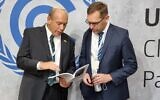 State Comptroller Matanyahu Englman (L) shows an English translation of his office's recent report on the climate performance of successive Israeli governments to the Latvian Auditor General, Rolands Irklis, during the COP26 UN climate conference in Glasgow, Scotland, November 4, 2021. (State Comptroller's Office)