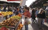 A woman shops at a street market in the center of Israel's Mediterranean coastal city of Tel Aviv on December 1, 2021. (MENAHEM KAHANA / AFP)
