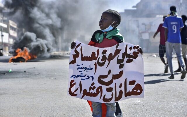 A Sudanese boy lifts a banner which reads in Arabic, 'imagine the fear of the military of chants on the streets,' during a rally in the capital Khartoum, on December 6, 2021. (AFP) A Sudanese boy lifts a banner which reads in Arabic, 'imagine the fear of the military of chants on the streets,' during a rally in the capital Khartoum, on December 6, 2021. (AFP)