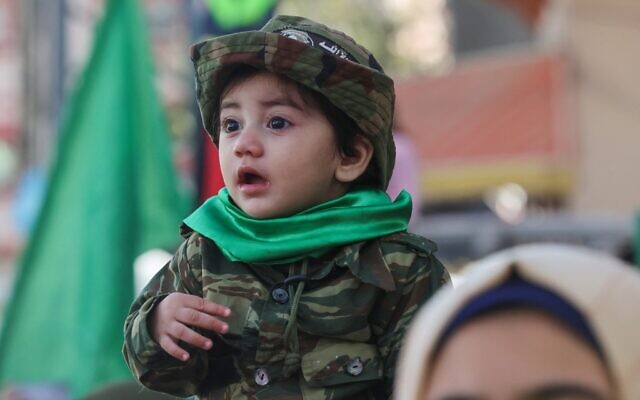 A child looks on as people participate in a rally in the Jabaliya refugee camp in the Gaza Strip, marking the 34th anniversary of the founding of Hamas which rules the coastal enclave, December 10, 2021. (Mohammed ABED / AFP) A child looks on as people participate in a rally in the Jabaliya refugee camp in the Gaza Strip, marking the 34th anniversary of the founding of Hamas which rules the coastal enclave, December 10, 2021. (Mohammed ABED / AFP)