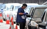 A health official collects a COVID-19 swab test at a drive-through testing site on Bondi beach in Sydney, on December 15, 2021, as rapidly-growing Omicron and Delta clusters brought more than 2,700 new cases nationally. (Mohammad Farooq/AFP)