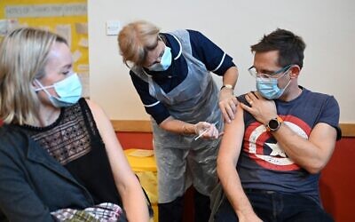 A man receives a dose of the Pfizer Covid-19 vaccine in a vaccination clinic set up at St Columba's Church in Sheffield on December 15, 2021 as the UK steps up the country's booster drive to fight a "tidal wave" of Omicron. (Photo by Oli SCARFF / AFP)