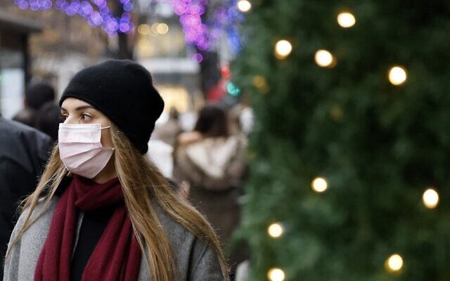 Shoppers, some wearing face coverings to combat the spread of COVID-19, walks past stores on the final Saturday before Christmas, on Oxford Street in London, on December 18, 2021. (Tolga Akmen/AFP)