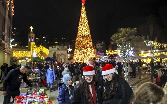 People gather at night around the giant Christmas tree outside the Greek Orthodox Church of the Annunciation in Israel's northern city of Nazareth on December 18, 2021. (Ahmad Gharabli/AFP) People gather at night around the giant Christmas tree outside the Greek Orthodox Church of the Annunciation in Israel's northern city of Nazareth on December 18, 2021. (Ahmad Gharabli/AFP)