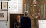 A visitor explores art works at an exhibition titled 'Vienna Falls in Line. The Politics of Art under National Socialism' showing Nazi artifacts at the city's Vienna Museum in Vienna, Austria, on November 9, 2021. (Joe Klamar/AFP)
