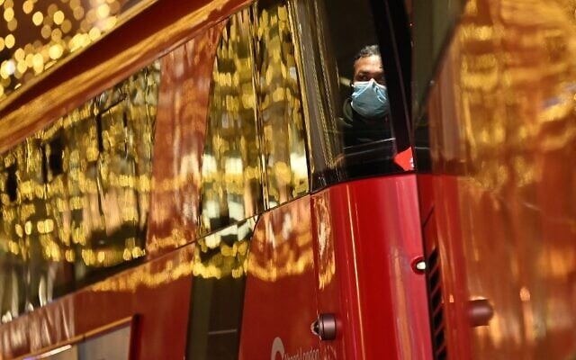 A passenger wearing a face covering to combat the spread of COVID-19 sits on a red double-decker bus traveling beneath Christmas lights in London on December 21, 2021. (Justin Tallis/AFP) A passenger wearing a face covering to combat the spread of COVID-19 sits on a red double-decker bus traveling beneath Christmas lights in London on December 21, 2021. (Justin Tallis/AFP)