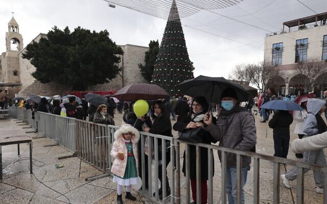 People gather outside the Church of the Nativity, revered as the site of Jesus Christ's birth, during Christmas celebrations in Bethlehem on December 24, 2021. (ABBAS MOMANI / AFP)