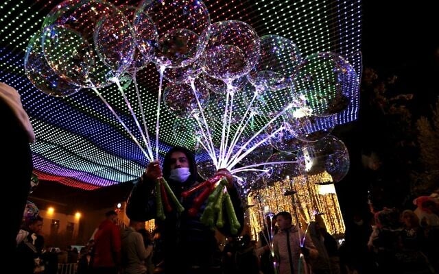 Vendors sell balloons to visitors in Manger Square on Christmas eve outside the Church of the Nativity, revered as the site of Jesus Christ's birth, in the biblical city of Bethlehem in the West Bank on December 24, 2021. (ABBAS MOMANI / AFP) Vendors sell balloons to visitors in Manger Square on Christmas eve outside the Church of the Nativity, revered as the site of Jesus Christ's birth, in the biblical city of Bethlehem in the West Bank on December 24, 2021. (ABBAS MOMANI / AFP)