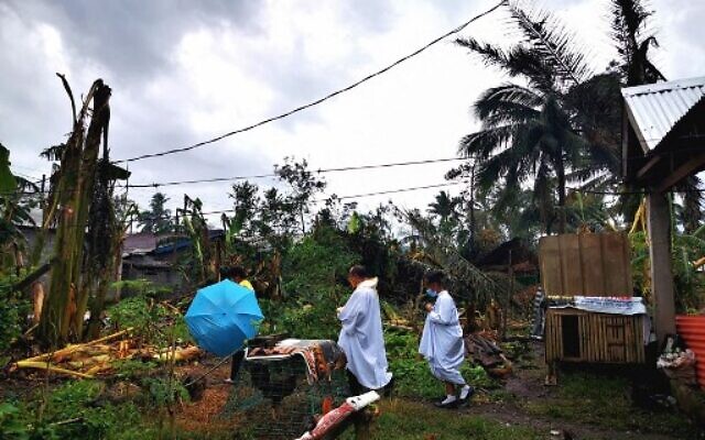 This photo taken on December 24, 2021, Roman Catholic priest Fr. Ricardo Virtudazo (center) walking among toppled banana trees caused by Super Typhoon Rai, as he visits typhoon-affected parishioners in Alegria, Surigao del Norte province.(Ferdinandh Cabrera/AFP) This photo taken on December 24, 2021, Roman Catholic priest Fr. Ricardo Virtudazo (center) walking among toppled banana trees caused by Super Typhoon Rai, as he visits typhoon-affected parishioners in Alegria, Surigao del Norte province.(Ferdinandh Cabrera/AFP)