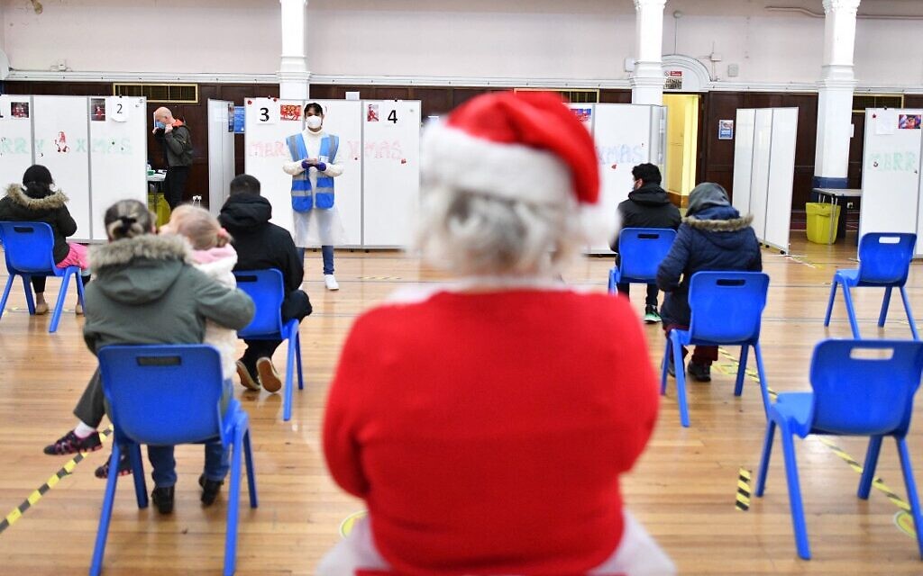 A volunteer looks on as people wait to receive a dose of the COVID19 vaccine at a pop-up coronavirus vaccination centre at the Redbridge Town Hall, east London on December 25, 2021 (JUSTIN TALLIS / AFP) A volunteer looks on as people wait to receive a dose of the COVID19 vaccine at a pop-up coronavirus vaccination centre at the Redbridge Town Hall, east London on December 25, 2021 (JUSTIN TALLIS / AFP)