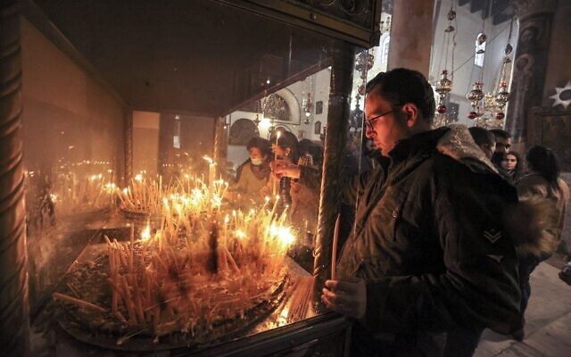 Milad Ayyad, a Palestinian Greek Orthodox Christian from Gaza, lights candles at the Greek Basilica at the Church of the Nativity, the traditional place of Christ's birth, in the biblical city of Bethlehem in the occupied West Bank, on December 26, 2021. (Hazem Bader/AFP) Milad Ayyad, a Palestinian Greek Orthodox Christian from Gaza, lights candles at the Greek Basilica at the Church of the Nativity, the traditional place of Christ's birth, in the biblical city of Bethlehem in the occupied West Bank, on December 26, 2021. (Hazem Bader/AFP)