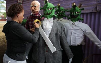 A woman tapes the word 'Omicron' to a handmade doll depicting the COVID-19 Omicron variant in Managua, Nicaragua, on December 27, 2021. (Oswaldo Rivas/AFP)
