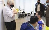 British Prime Minister Boris Johnson (L) visits a COVID-19 vaccination center at the Rainbow Pharmacy in the Open University Campus, Walton Hall, in Milton Keynes on December 29, 2021. (Geoff PUGH / POOL / AFP)