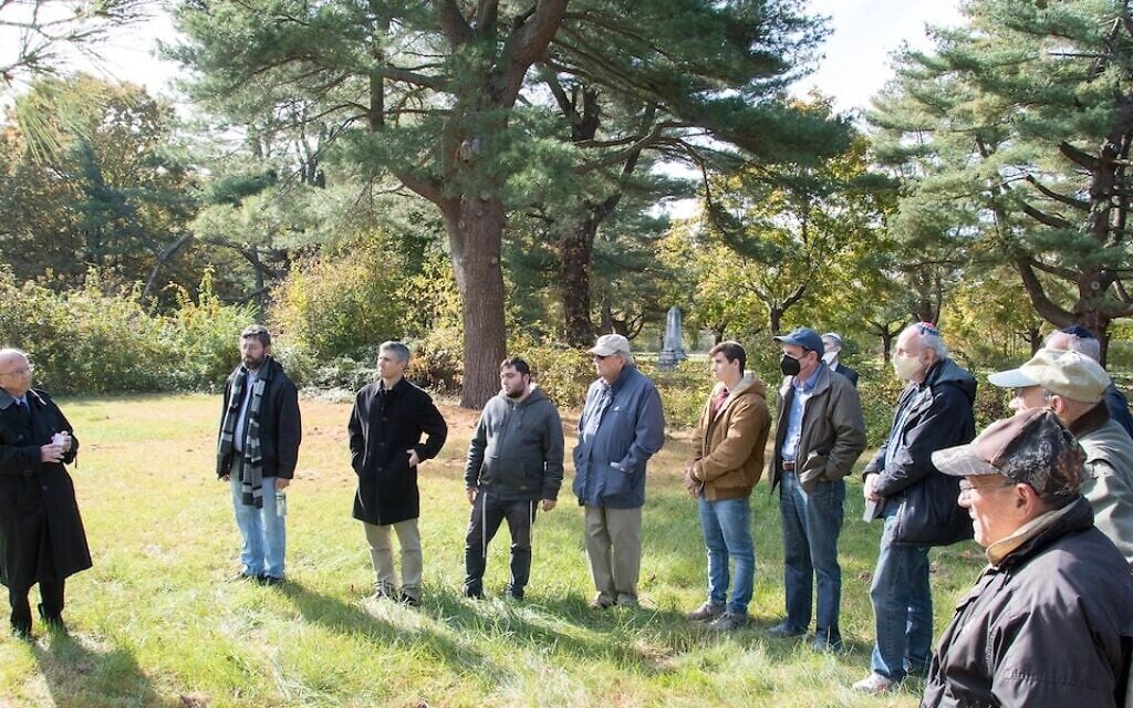 Members of the Men’s Club at the North Shore Jewish Center in Port Jefferson, New York, hold a ceremony at the Jewish section of the cemetery of what had been the Central Islip Psychiatric Center, November 11, 2021. (Ray Cella/ via JTA)