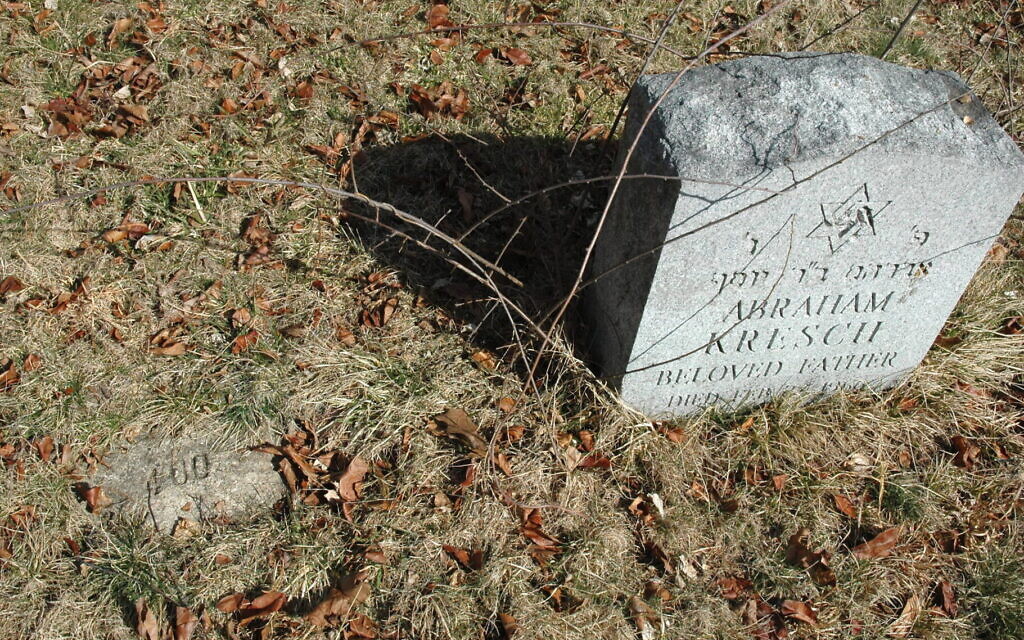 A number marks a Jewish grave, left, at the former Central Islip Psychiatric Center on New York's Long Island. A stone at right was added after the hospital began working with a Jewish burial society. (Patricia Desrochers/Touro Law Center/ via JTA)