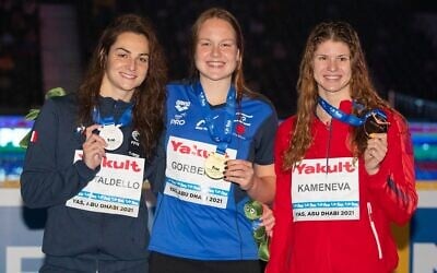 Israel's Anastasia Gorbenko poses with her gold medal -- alongside France's silver medalist Brill Gastaldello (left) and Russia's Maria Kamaneva, the bronze medalist -- after winning the 100-meter individual medley on December 19, 2021, at the World Swimming Championships in Abu Dhabi. It was Gorbenko's second gold at the championships (Israel Swimming Association) Israel's Anastasia Gorbenko poses with her gold medal -- alongside France's silver medalist Brill Gastaldello (left) and Russia's Maria Kamaneva, the bronze medalist -- after winning the 100-meter individual medley on December 19, 2021, at the World Swimming Championships in Abu Dhabi. It was Gorbenko's second gold at the championships (Israel Swimming Association)