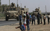 In this July 26, 2017, file photo, Syrians look at a US armored vehicle convoy on a road that leads to Raqqa, northeast Syria. (AP Photo/Hussein Malla, File)
