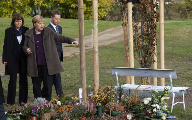 Then-German Chancellor Angela Merkel lays down flowers at the memorial place and freshly planted trees for the victims of the neo-Nazi 'Nationalist Socialist Underground' NSU in Zwickau, eastern Germany, Monday, Nov. 4, 2019. (AP Photo/Jens Meyer)