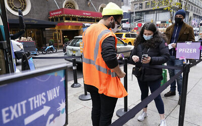 A health care worker, left, checks people in at a NYC mobile vaccine clinic in Midtown Manhattan, Dec. 6, 2021 (AP Photo/Mary Altaffer)