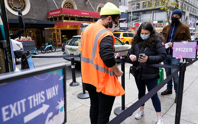 A health care worker, left, checks people in at a NYC mobile vaccine clinic in Midtown Manhattan, Dec. 6, 2021 (AP Photo/Mary Altaffer) A health care worker, left, checks people in at a NYC mobile vaccine clinic in Midtown Manhattan, Dec. 6, 2021 (AP Photo/Mary Altaffer)