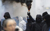 Protestors light flares during a demonstration against measures to battle the coronavirus pandemic in Vienna, Austria, on Dec. 11, 2021. New research indicates that far-right extremists and white supremacists are gaining new followers and influence by co-opting conspiracy theories about COVID-19.  (AP Photo/Florian Schroetter, File)