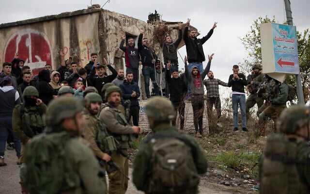 Israeli soldiers stand between Palestinians and a Jewish settlers following a settler attack on the West Bank village of Burqa, December 17, 2021 after the funeral of Yehuda Dimentman, 25, who was killed in a shooting attack by a Palestinian gunman (AP Photo/Majdi Mohammed) Israeli soldiers stand between Palestinians and a Jewish settlers following a settler attack on the West Bank village of Burqa, December 17, 2021 after the funeral of Yehuda Dimentman, 25, who was killed in a shooting attack by a Palestinian gunman (AP Photo/Majdi Mohammed)