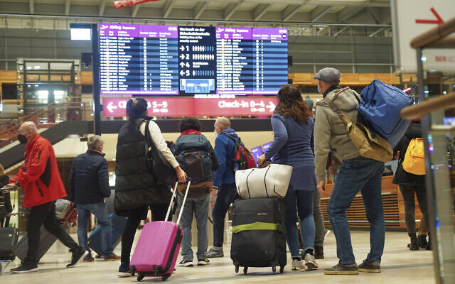 Travelers stand in front of an information board at BER Airport in Berlin, Germany, Dec. 18, 2021. (Joerg Carstensen/dpa via AP)
