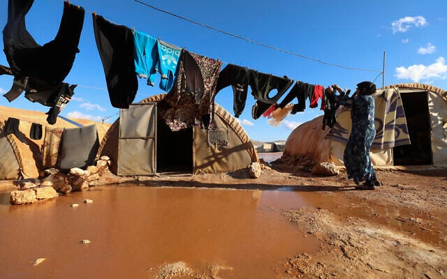 A woman hangs laundry in a flooded refugee camp in Idlib province, Syria, December 21, 2021. (AP Photo/Ghaith Alsayed) A woman hangs laundry in a flooded refugee camp in Idlib province, Syria, December 21, 2021. (AP Photo/Ghaith Alsayed)