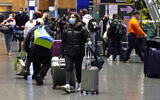 Travelers trek through Terminal E at Logan Airport, on December 21, 2021, in Boston. (AP/Charles Krupa)