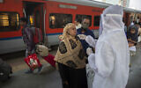A health worker takes a swab sample of a traveler to test for COVID-19 at a train station in Mumbai, India, December 30, 2021. (AP Photo/Rafiq Maqbool)