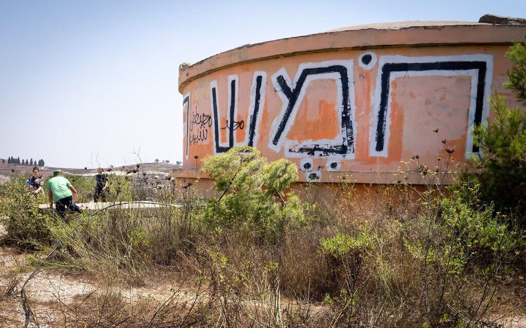 People walk by the water tower on the ruins of Homesh, August 27, 2019. (Hillel Meir/Flash90) People walk by the water tower on the ruins of Homesh, August 27, 2019. (Hillel Meir/Flash90)