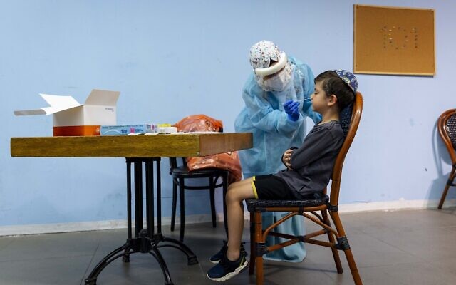 A Magen David Adom worker takes a swab sample for a COVID-19 rapid antigen test from a young boy, at a testing center in Jerusalem, on September 26, 2021. (Olivier Fitoussi/ Flash90) A Magen David Adom worker takes a swab sample for a COVID-19 rapid antigen test from a young boy, at a testing center in Jerusalem, on September 26, 2021. (Olivier Fitoussi/ Flash90)