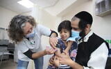 Children aged 5-11 receive their first dose of a COVID-19 vaccine, at Clallit vaccination center in Tzfat, on December 3, 2021. (David Cohen/Flash90)