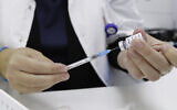 An Israeli health worker prepares a dose of the COVID-19 vaccine at a Maccabi Healthcare Services center in Katzrin, Golan Heights, December 12, 2021. (Michael Giladi/Flash90)