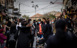 Israelis, some wearing face masks, shop at Jerusalem's Mahane Yehuda market, December 12, 2021. (Yonatan Sindel/Flash90)