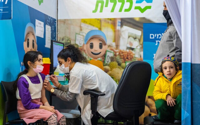 A girl receives a dose of the COVID-19 vaccine at a Clalit vaccine center in Jerusalem on December 21, 2021. (Olivier Fitoussi/Flash90)