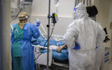 An illustrative photo of medical workers wearing protective gear tending to a patient in the coronavirus ward at Hadassah Hospital Ein Kerem in Jerusalem, on December 27, 2021. (Olivier Fitoussi/Flash90)