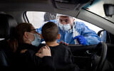 Health care workers test Israelis in a drive through complex to check if they have been infected with the coronavirus in Jerusalem, on December 29, 2021.  (Yonatan Sindel/Flash90)