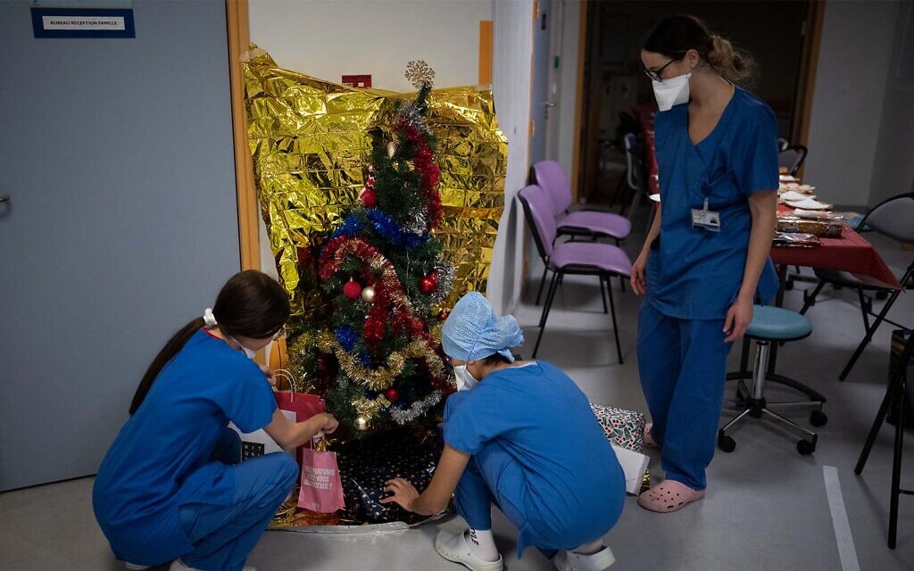 Hospital workers place gifts under a Christmas tree in the COVID-19 intensive care unit at la Timone hospital in Marseille, southern France, December 24, 2021. (AP Photo/Daniel Cole)