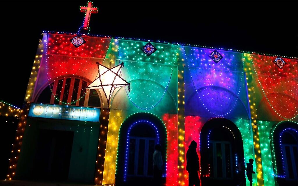 People walk past an illuminated church ahead of Christmas in Ahmedabad, India, December 22, 2021. (AP Photo/Ajit Solanki)