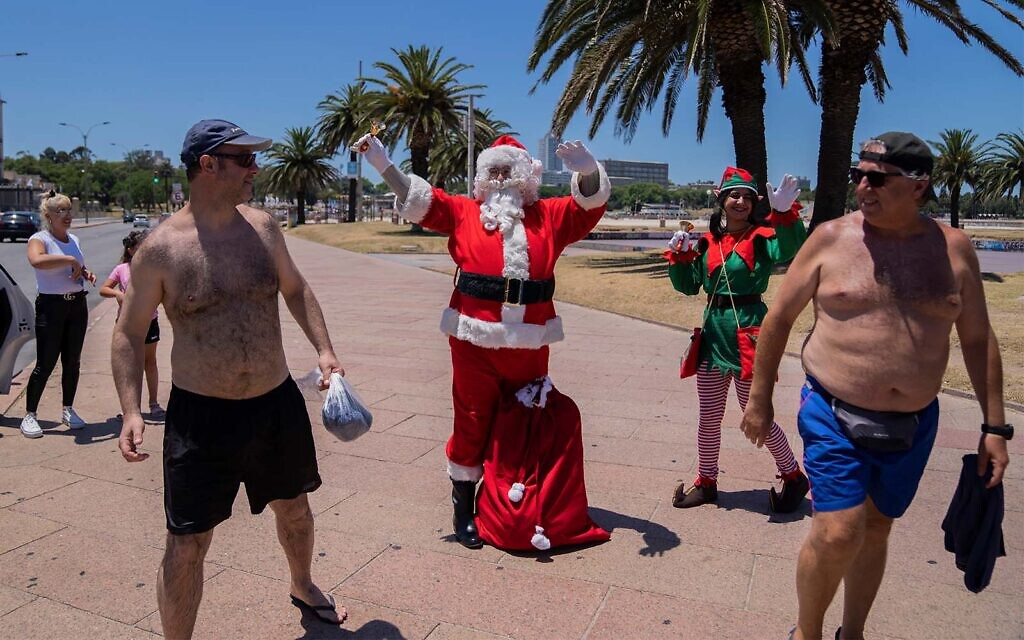 Dressed as Santa Claus, Washington Gularte greets beach goers leaving Ramirez beach on Christmas Eve in Montevideo, Uruguay, December 24, 2021. (AP Photo/Matilde Campodonico)