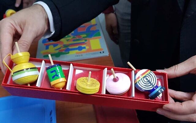 Rabbi Moti Grumach with some Hanukkah-styled Japanese koma tops and traditional dreidels. (Courtesy/Moti Grumach via JTA)